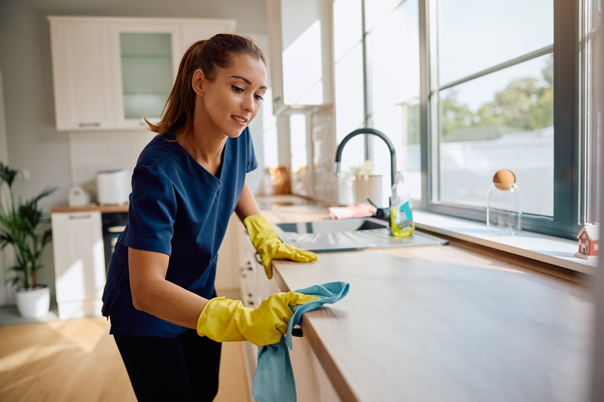 Young housemaid cleaning the kitchen counter