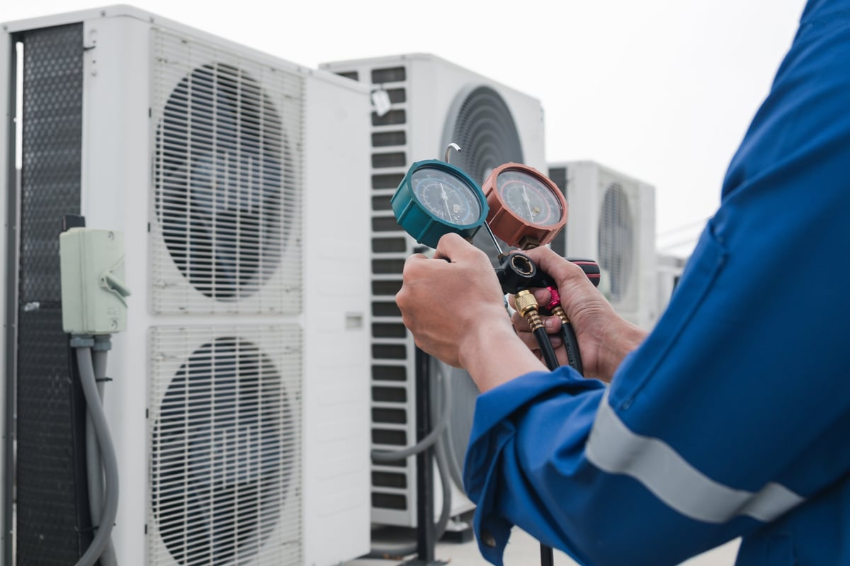 Technician checking air conditioner, measuring equipment for filling air conditioners
