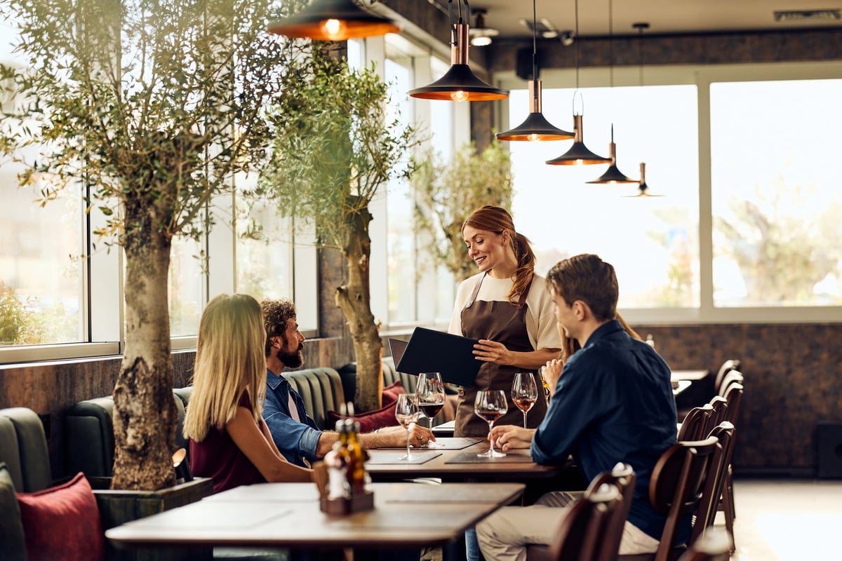 Diners enjoy a cozy meal with professional waitress service in a trendy restaurant.