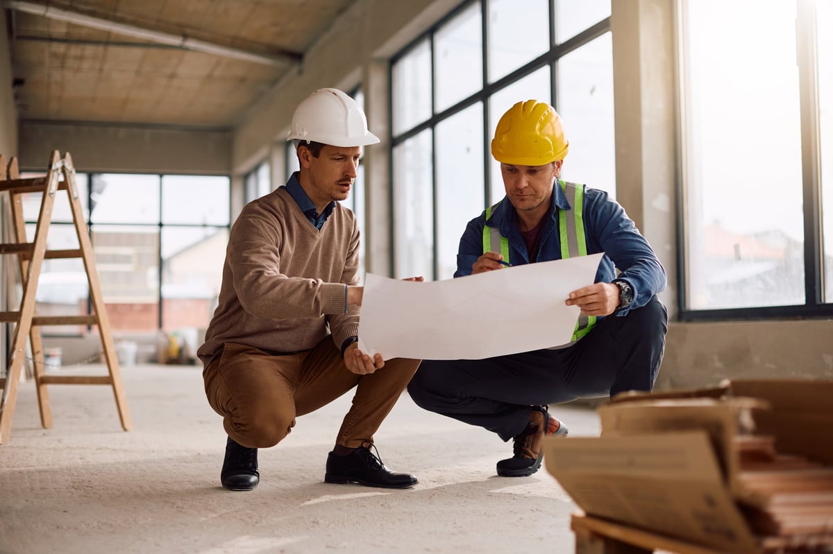 Project manager and worker reviewing plans at construction site