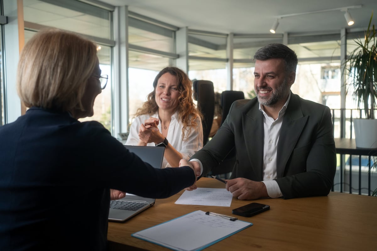 Young happy couple came to a successful agreement with their agent during a meeting in the office