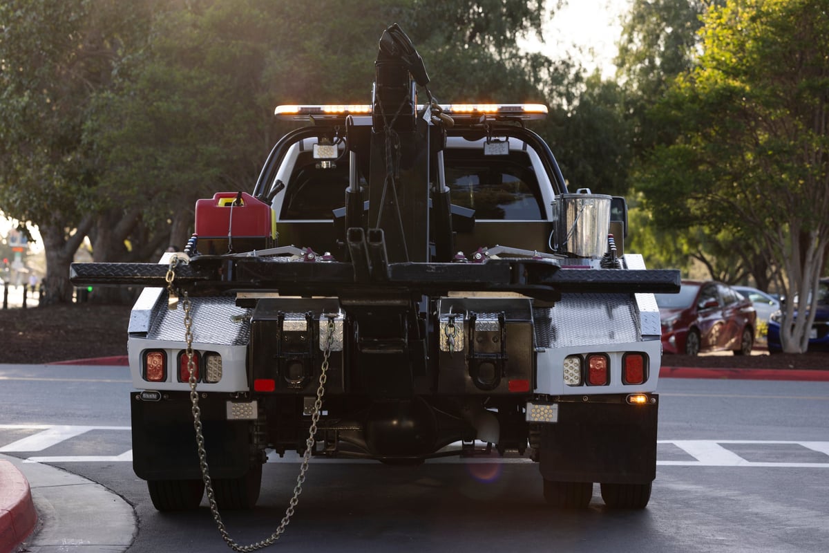 A tow truck illuminated by sunset light on a street
