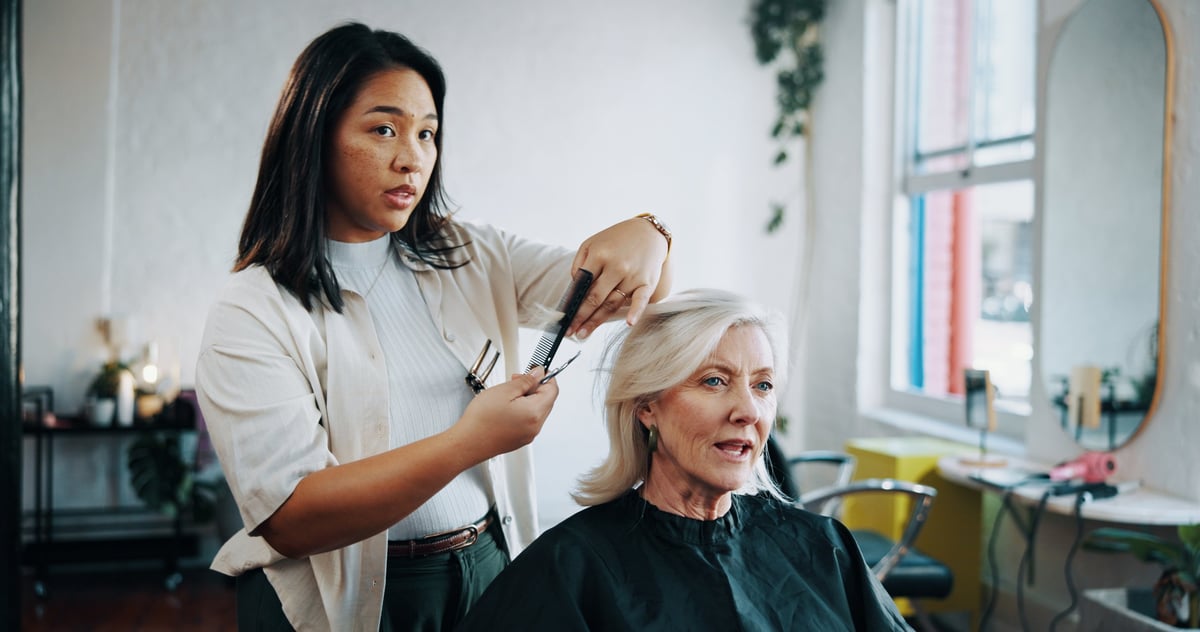 Mature woman, hairdresser and scissors with discussion at salon, hairstyle and decision for change. People, hair care and grooming services with tools, talk and customer experience at beauty parlor