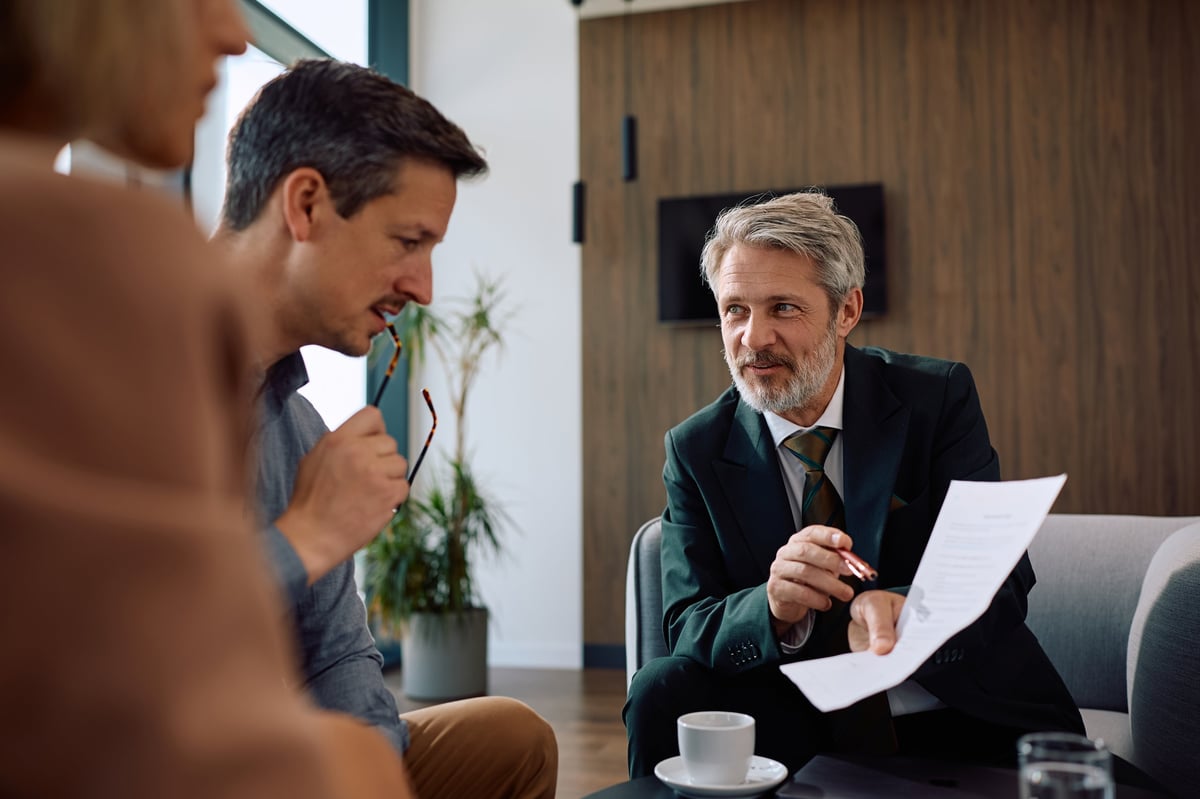 Smiling insurance agent analyzing financial reports with a couple on a meeting in the office
