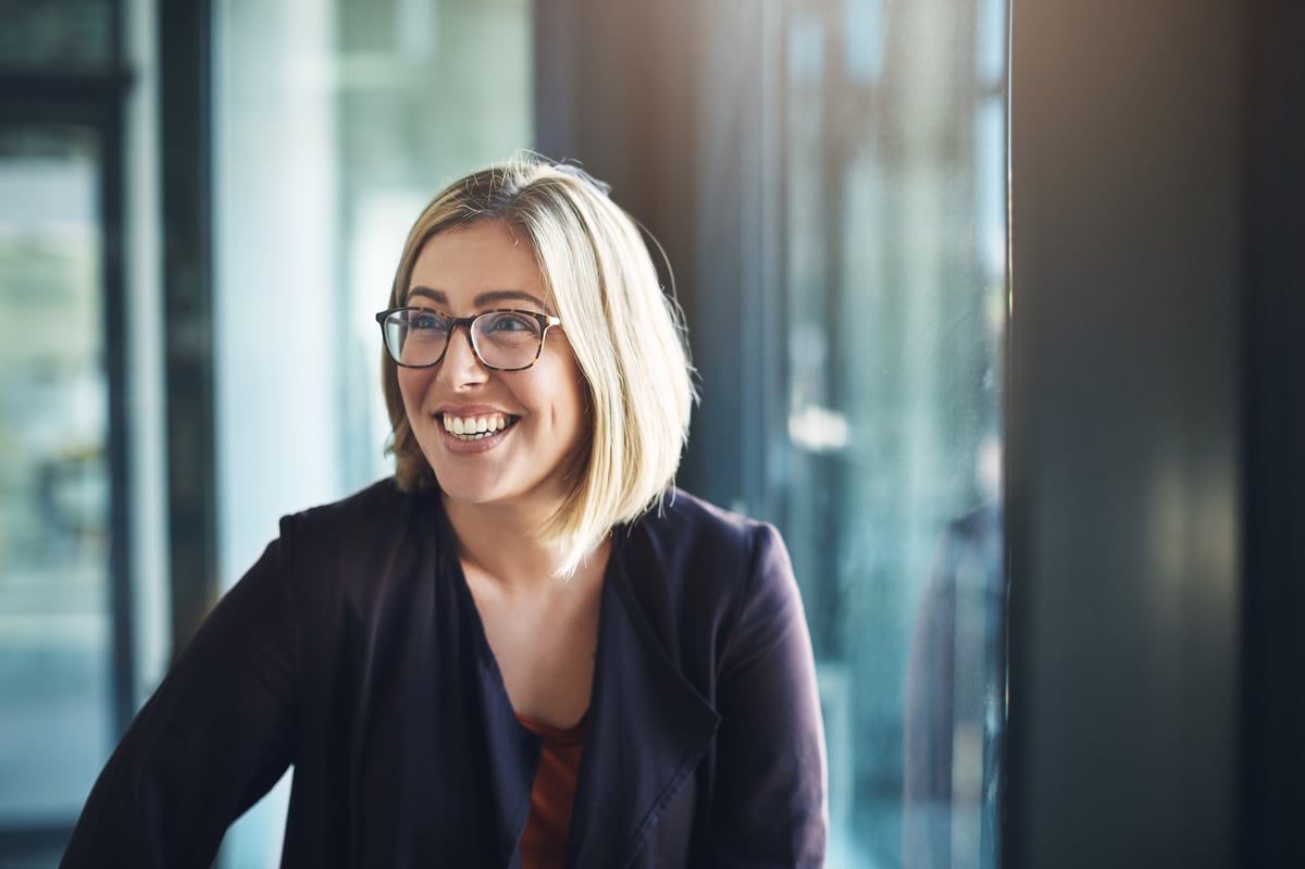 Happy businesswoman in a modern office confident that AI is handling calls